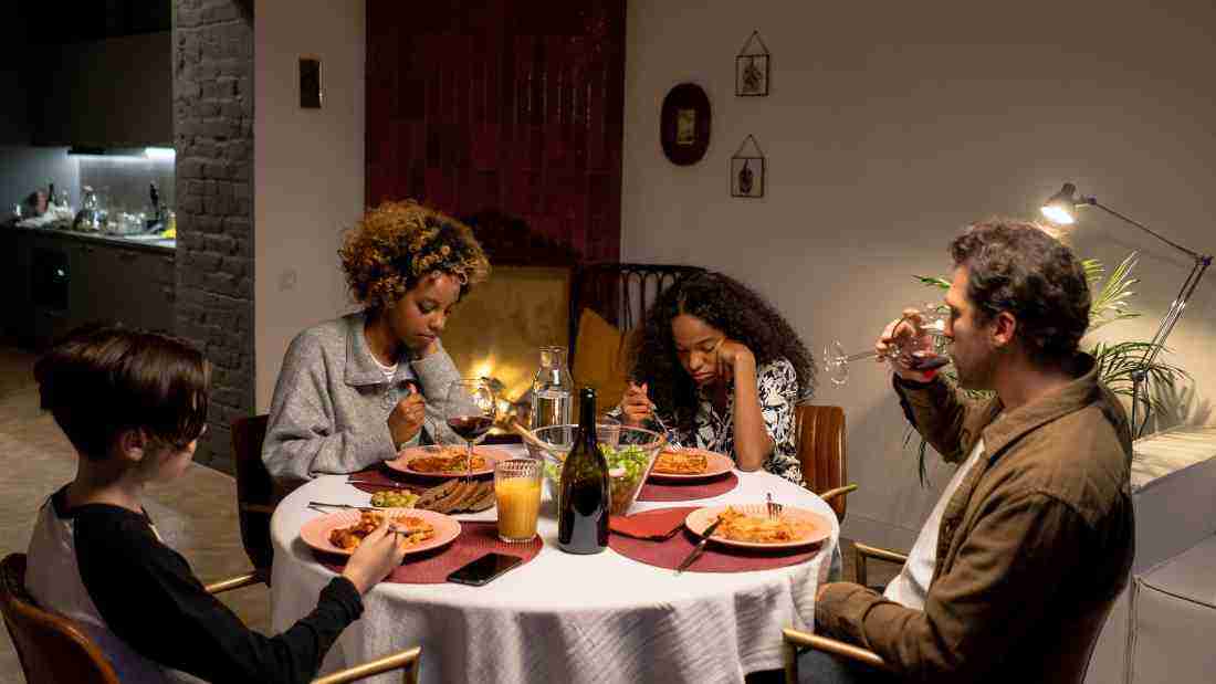 A family eating dinner but not looking at each other or talking