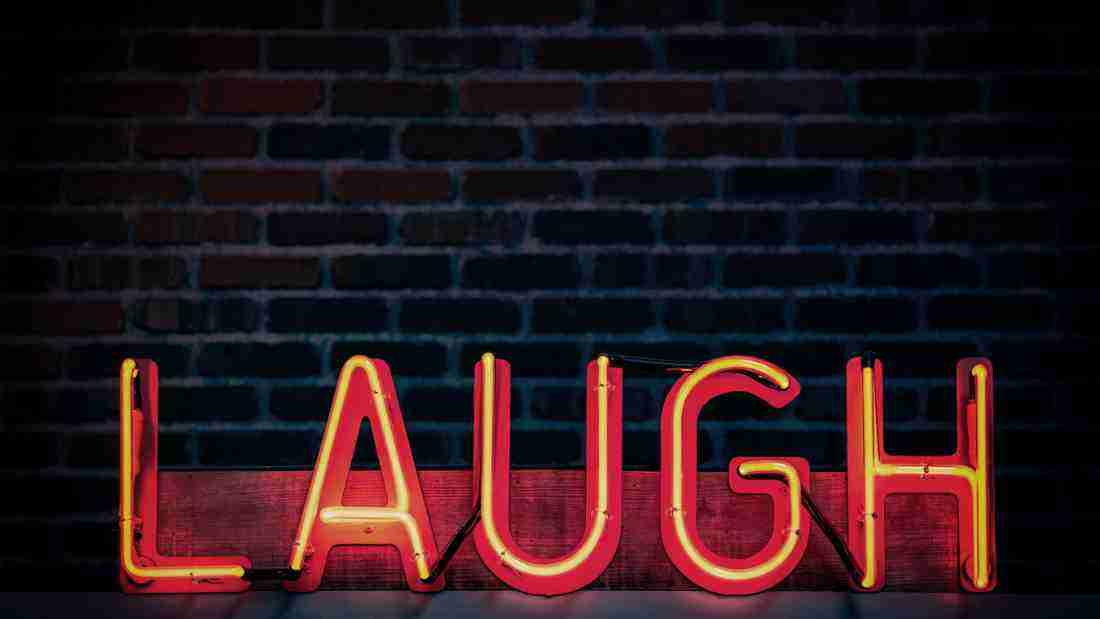 The word LAUGH lit up in neon lights