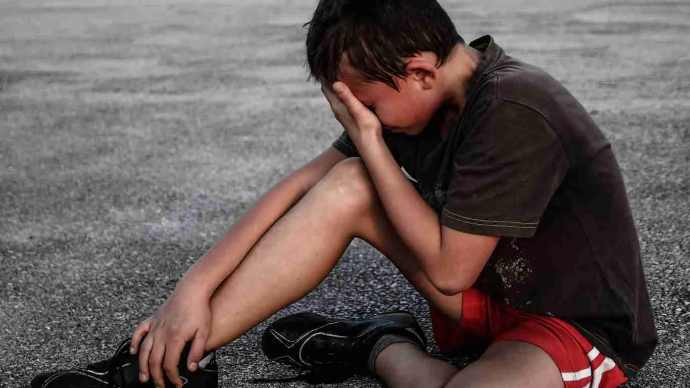 A young boy sitting on the floor and crying