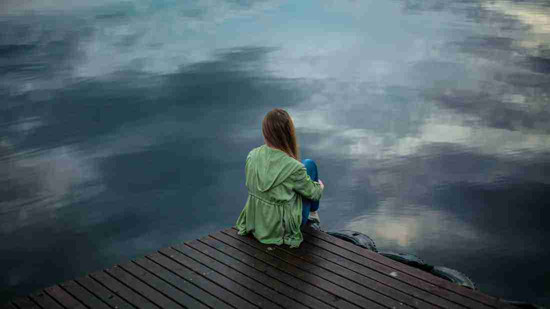 A lonely woman staring at a lake shrouded in fog