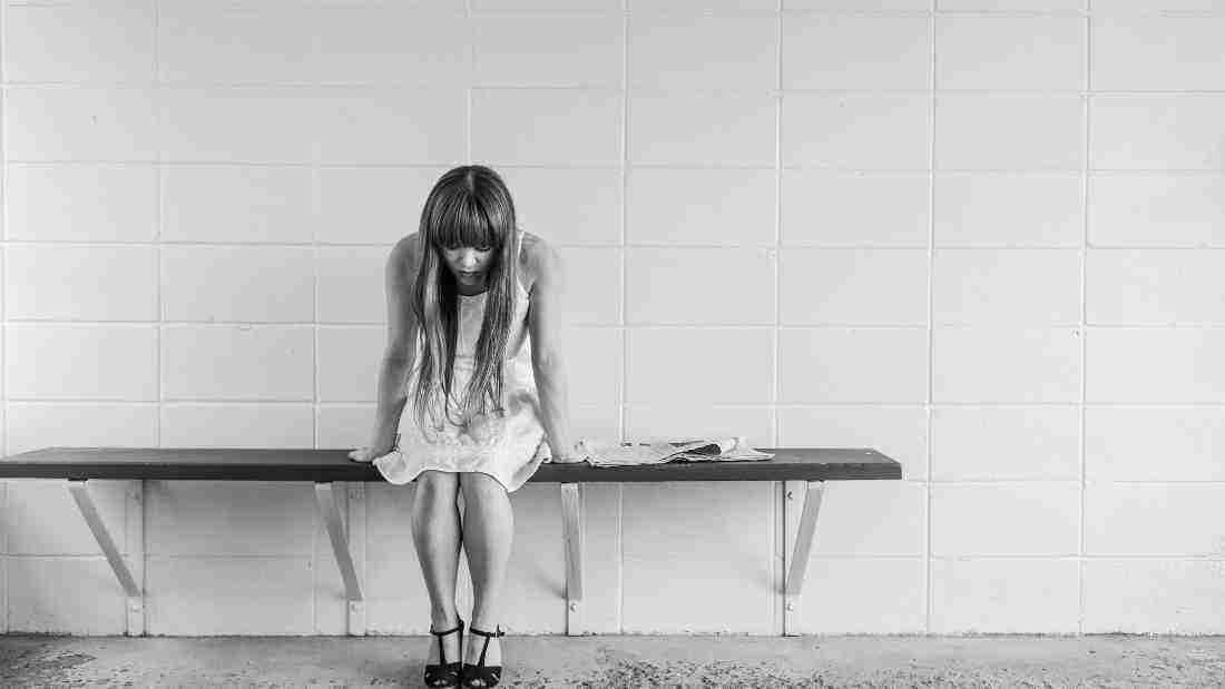 A lonely woman sitting on a bench and looking miserable