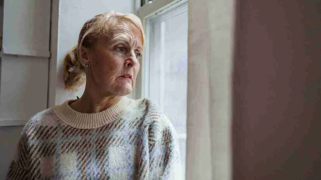 A sad old lady gazing out of a window