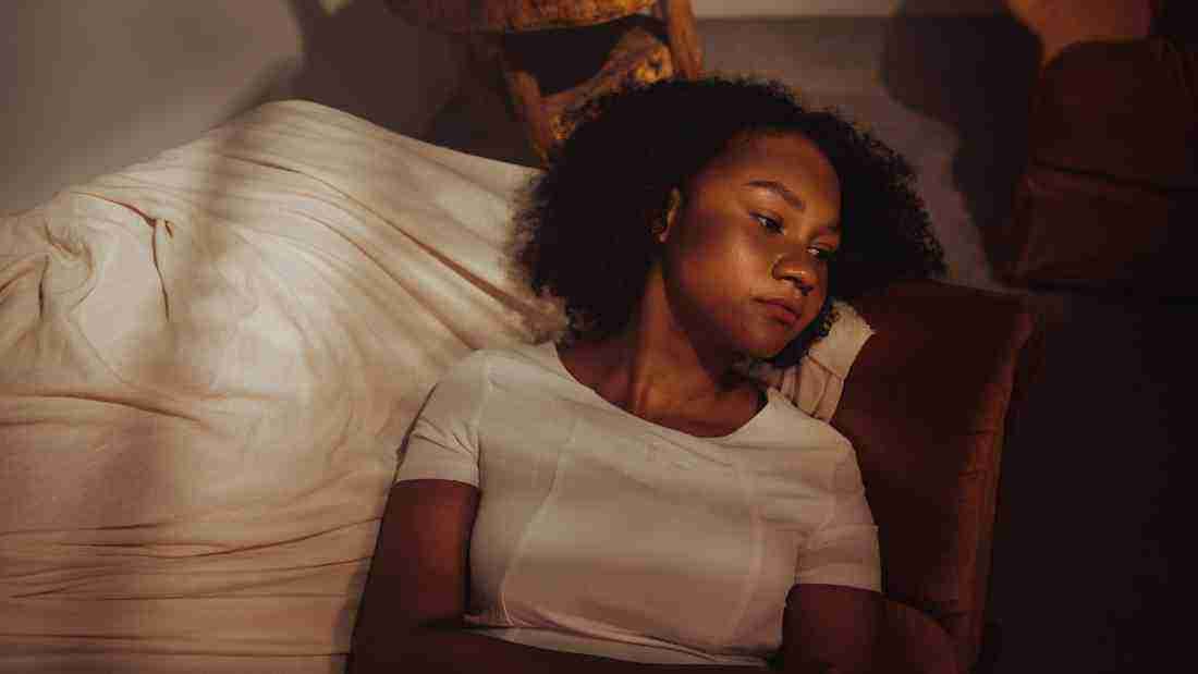 A depressed woman lying in bed in the dark