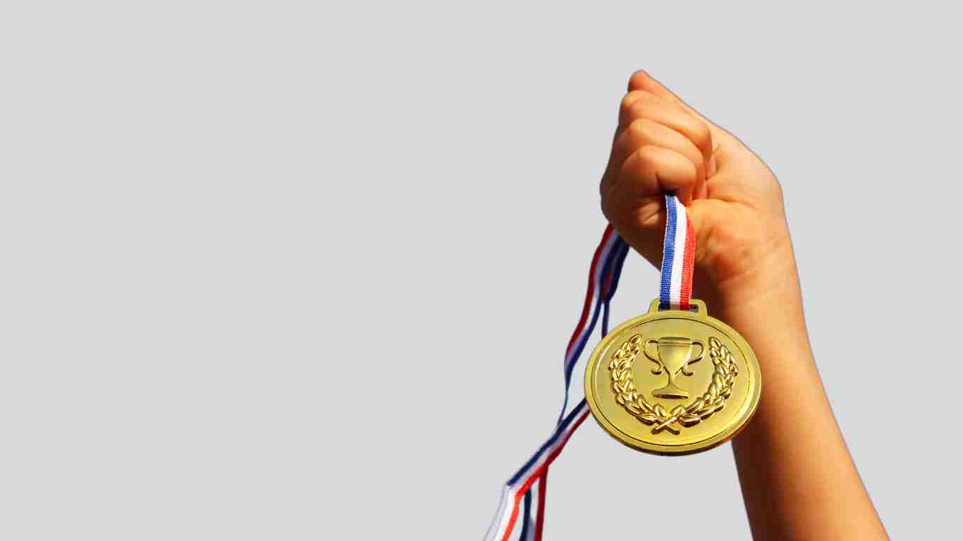 A young woman holding up a gold medal