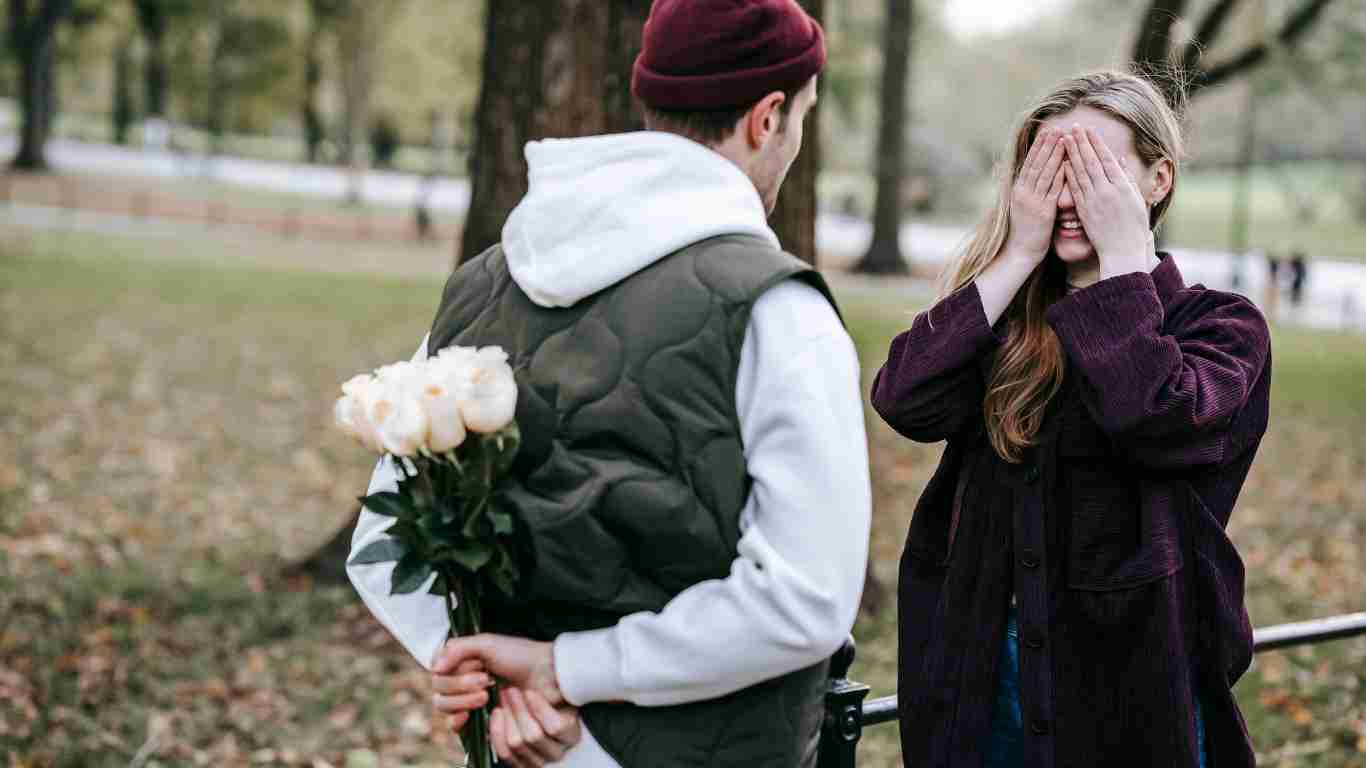 A man presenting a bouquet of white roses to his girlfriend