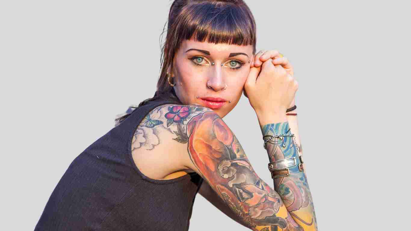 A rebellious woman covered in tattoos and staring defiantly into the camera