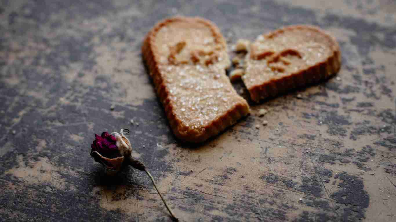 A heart-shaped cookie, lying broken on the floor