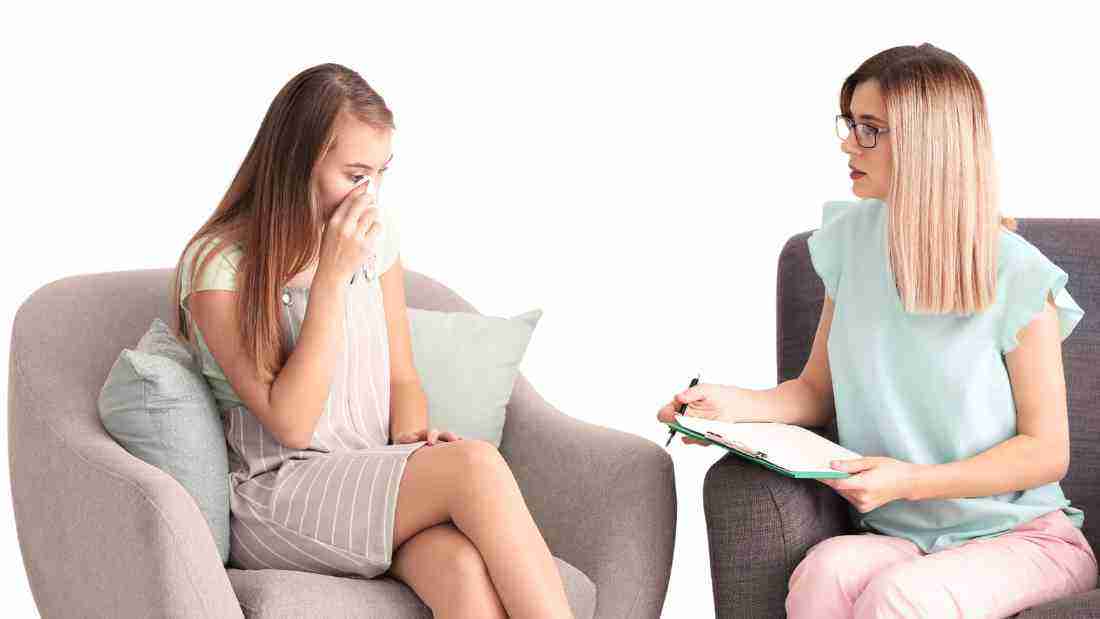 A young woman crying as she talks to her therapist
