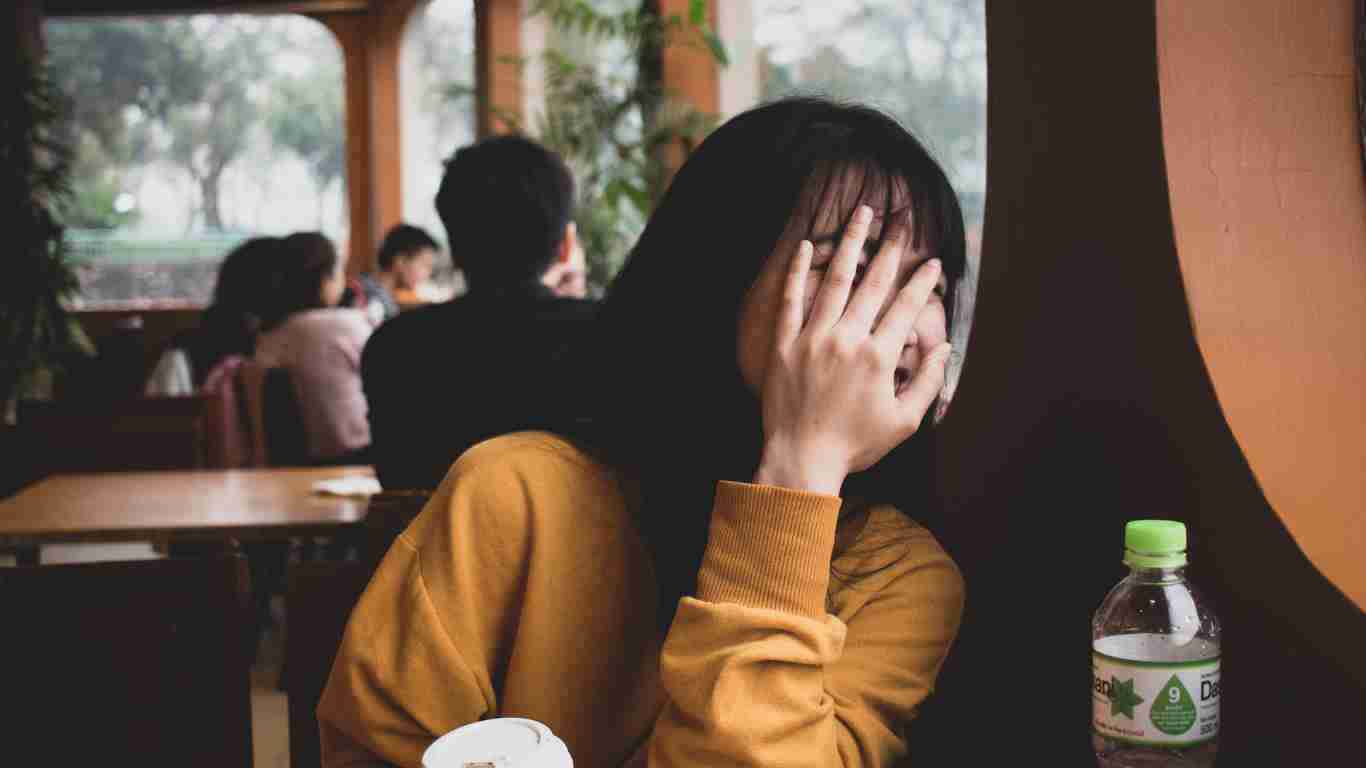 A woman in a coffee shop hiding her face because she is shy
