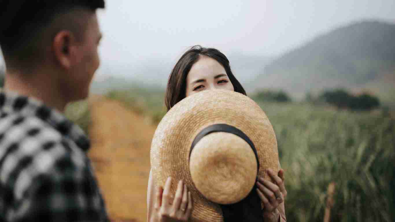 A woman peeking out from behind a big sun hat