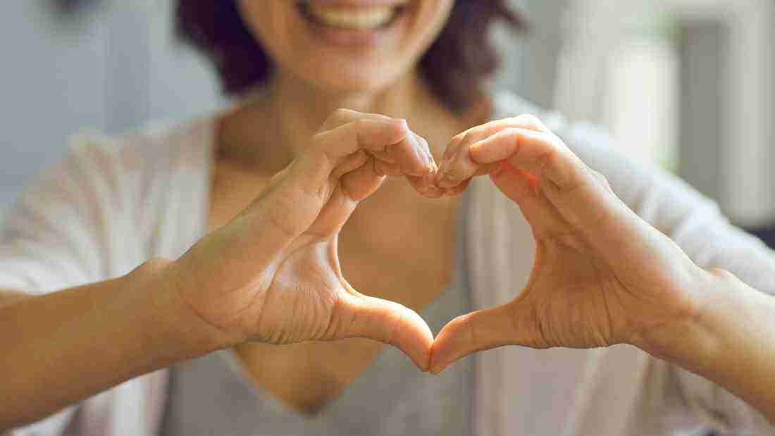 A woman making the shape of a heart using her hands