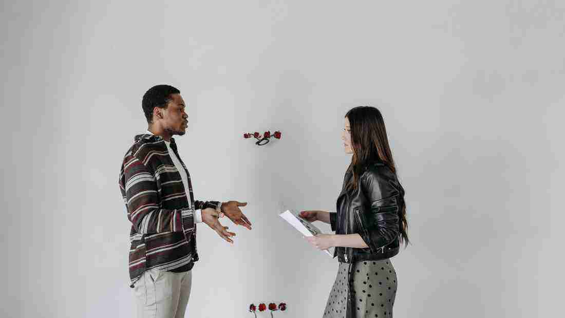 Man gesticulating as he talks to a woman