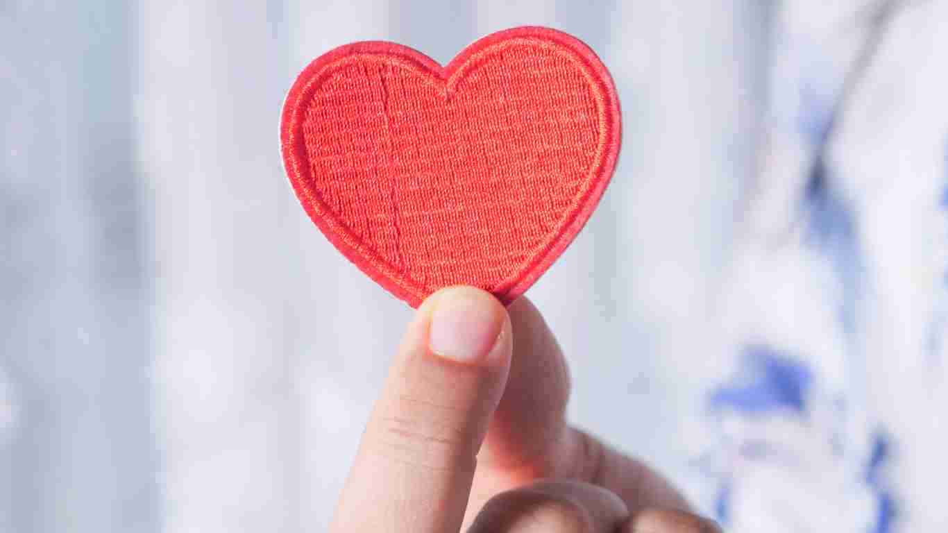 A hand holding a small heart, denoting empathy