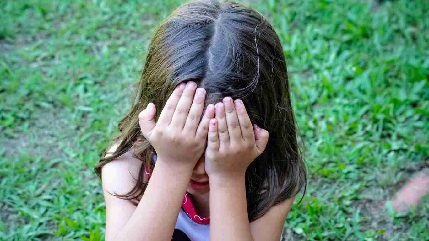 A little girl covering her face as she cries