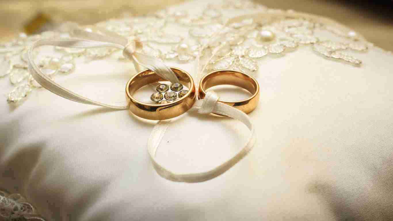 Two gold wedding rings on a silk pillow