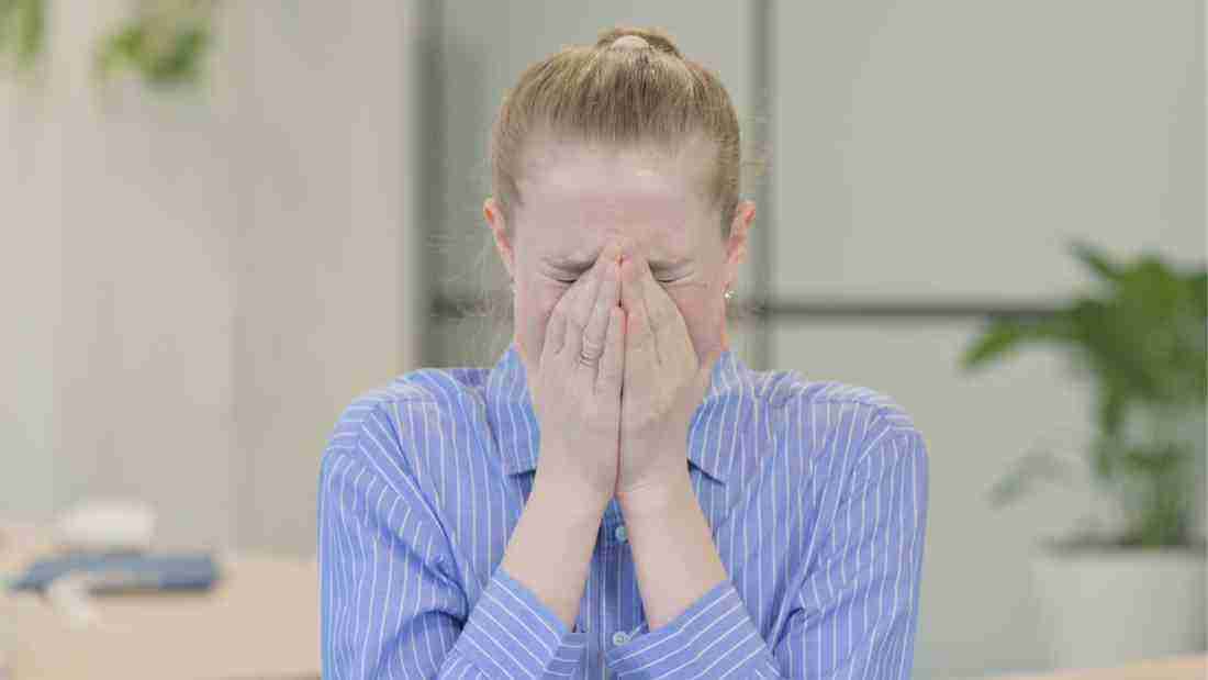 A distraught woman hiding her face behind her hands