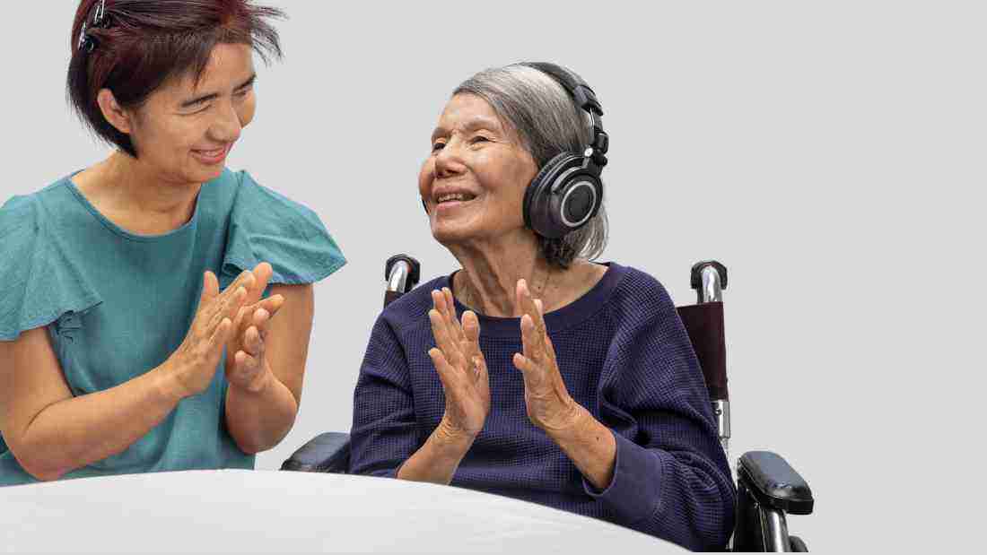 An old lady listening to music on headphones with a therapist