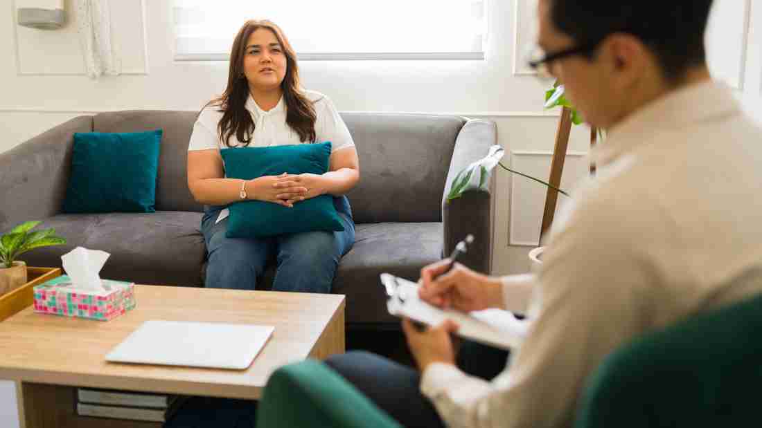A woman holding a cushion for comfort as she talks to her therapist