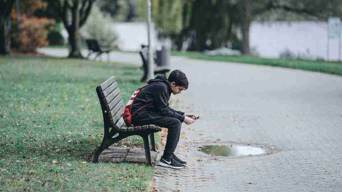 Depressed boy sitting alone at the park
