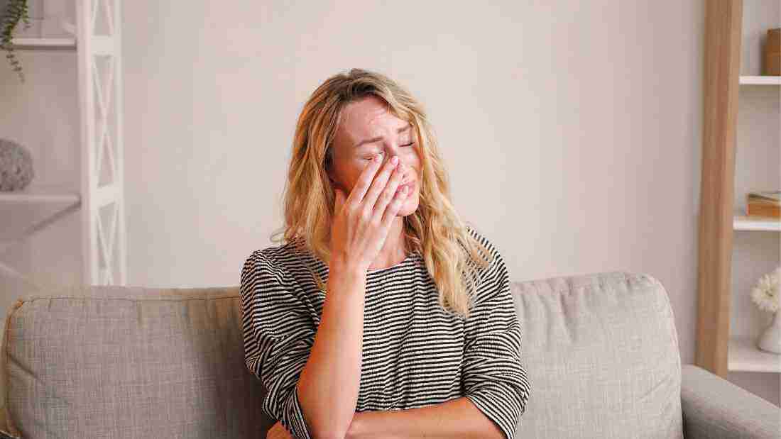A woman crying alone on a sofa