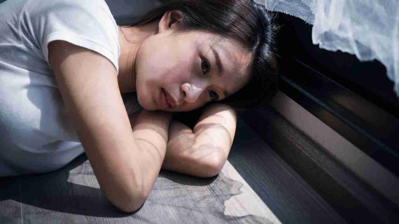A very depressed woman leaning on a window sill