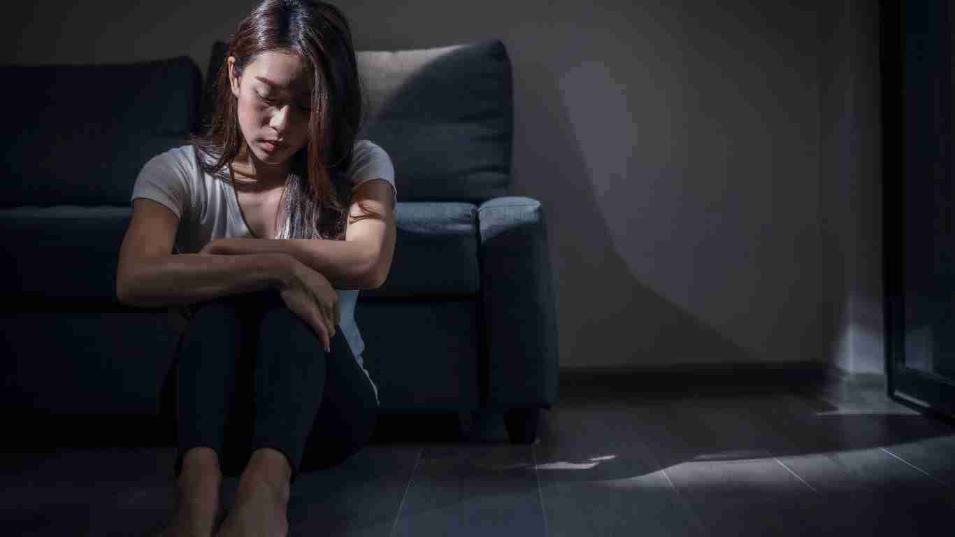 A depressed young woman sitting alone in the dark