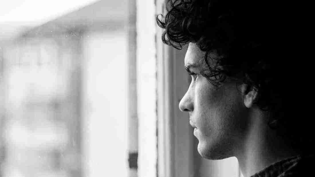 A sad young man gazing out of the window