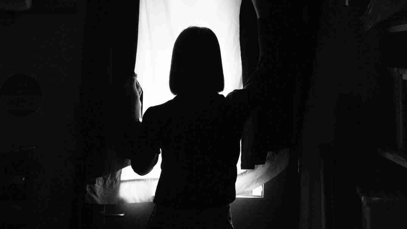 A woman standing in the darkness, looking totally isolated