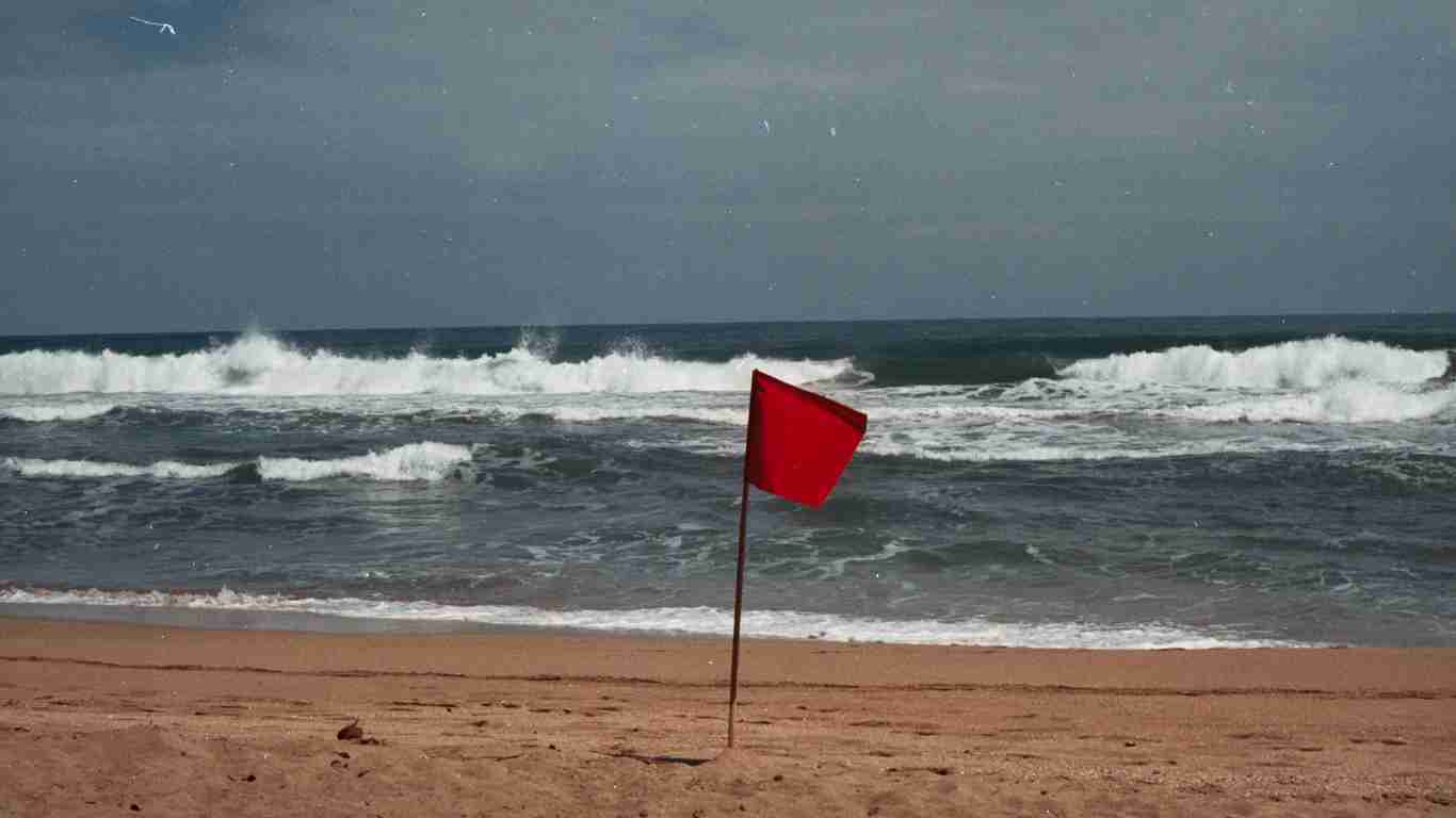 A red flag fluttering on a beach