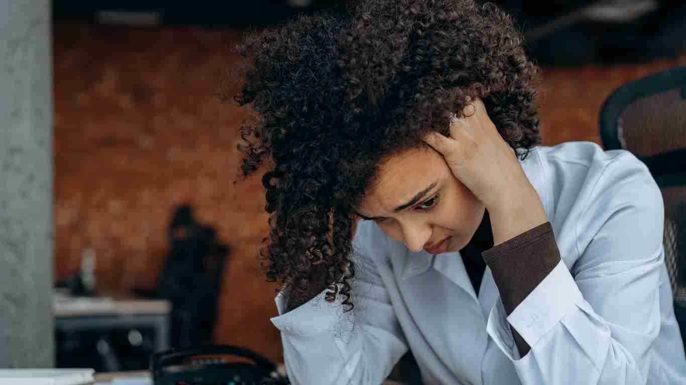 A woman holding her head in her hands as she struggles with the aftermath of psychological trauma