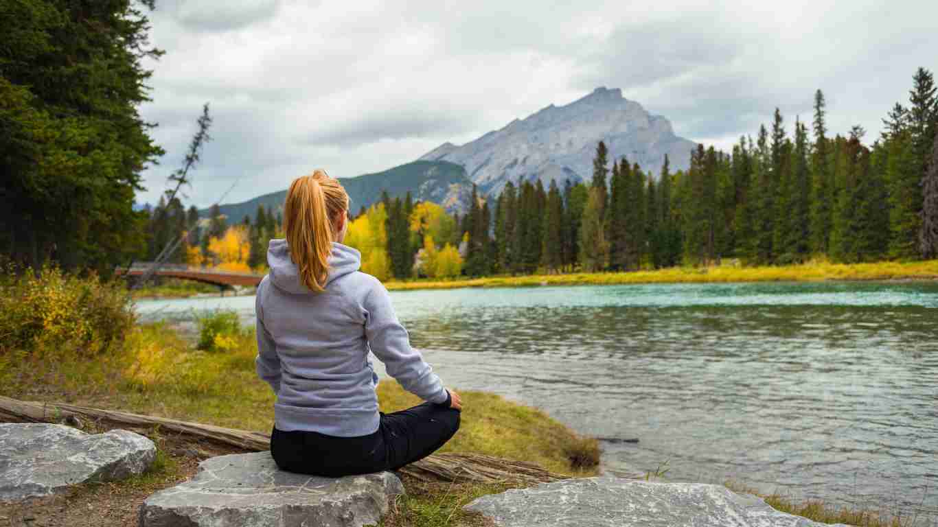 A woman meditating beside a beautiful lake