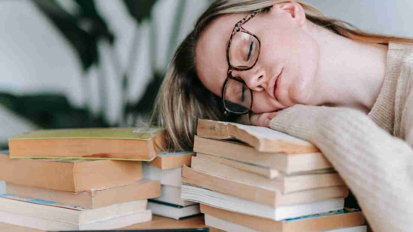 A woman fast asleep on a pile of books