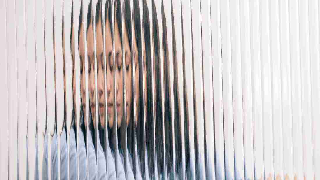 A confused woman viewed through opaque glass, symbolizing the impact of abuse