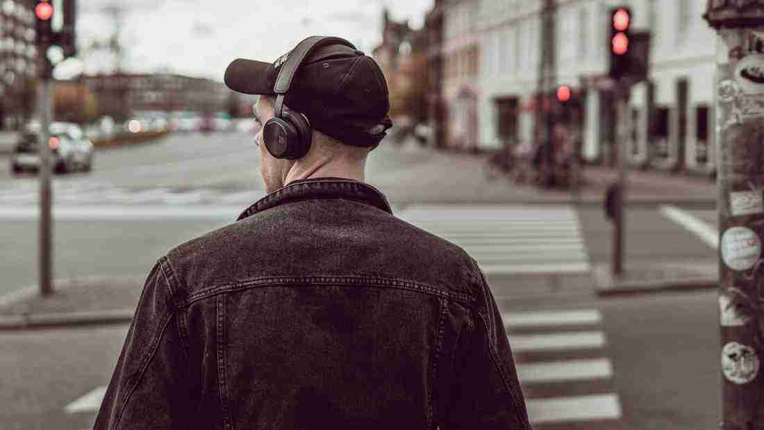 A man listening to music on his headphones as he crosses the street