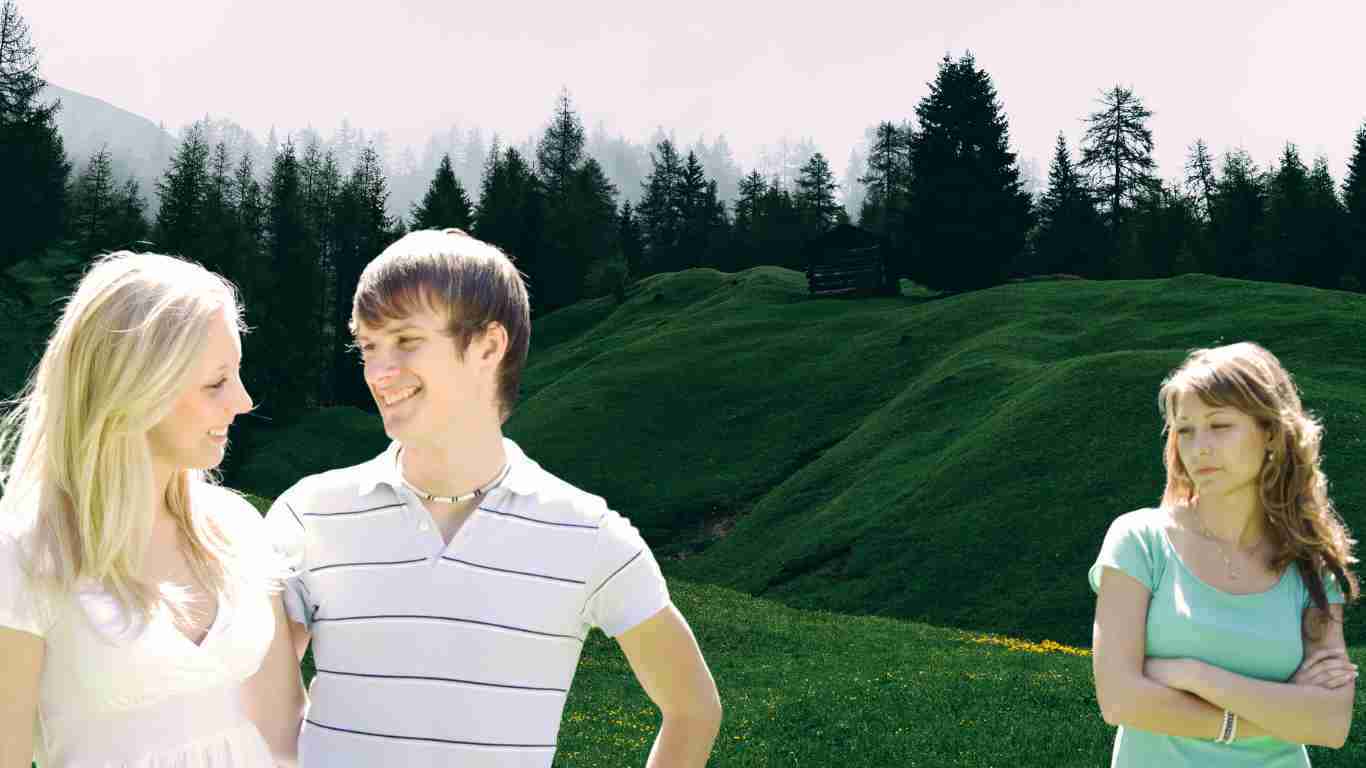 A man flirting with another woman in front of his partner