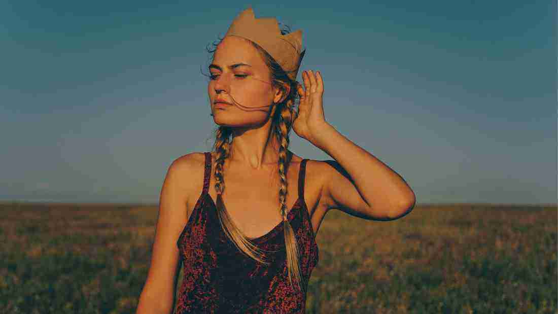 Woman walking through a meadow wearing a paper crown