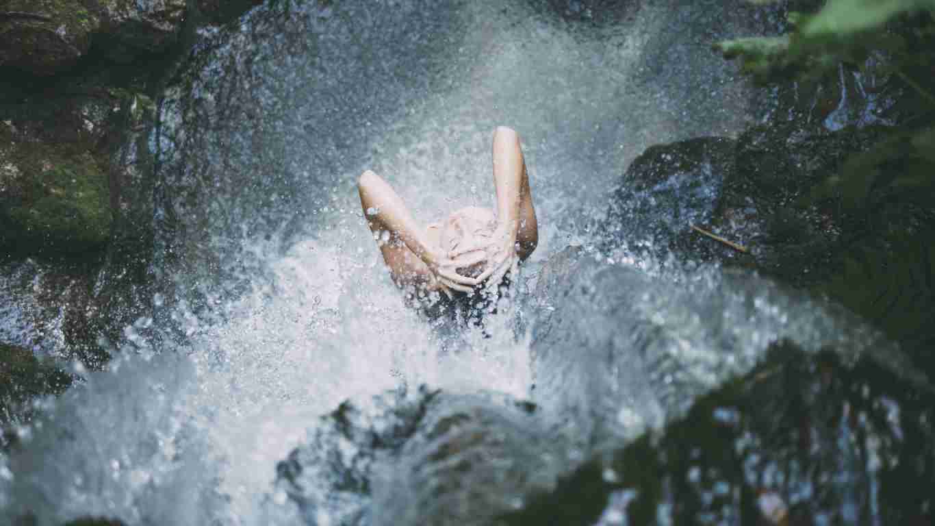 A woman standing under a waterfall