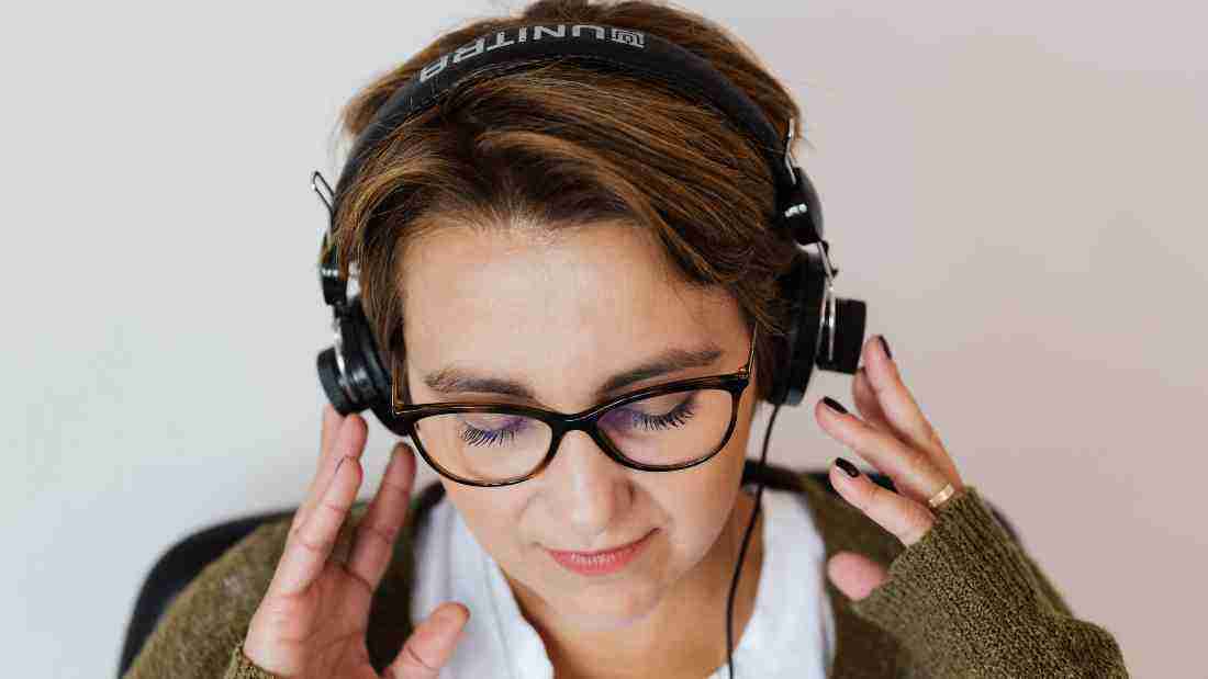 A middle aged woman listening to a song