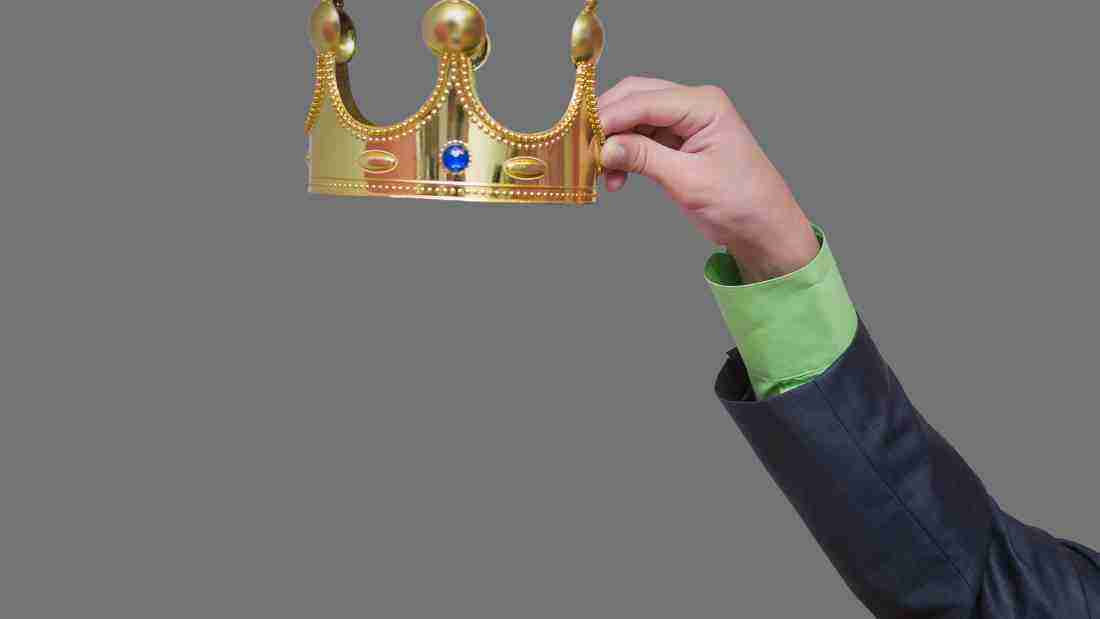 A hand holding a crown, symbolizing grandiose aspirations
