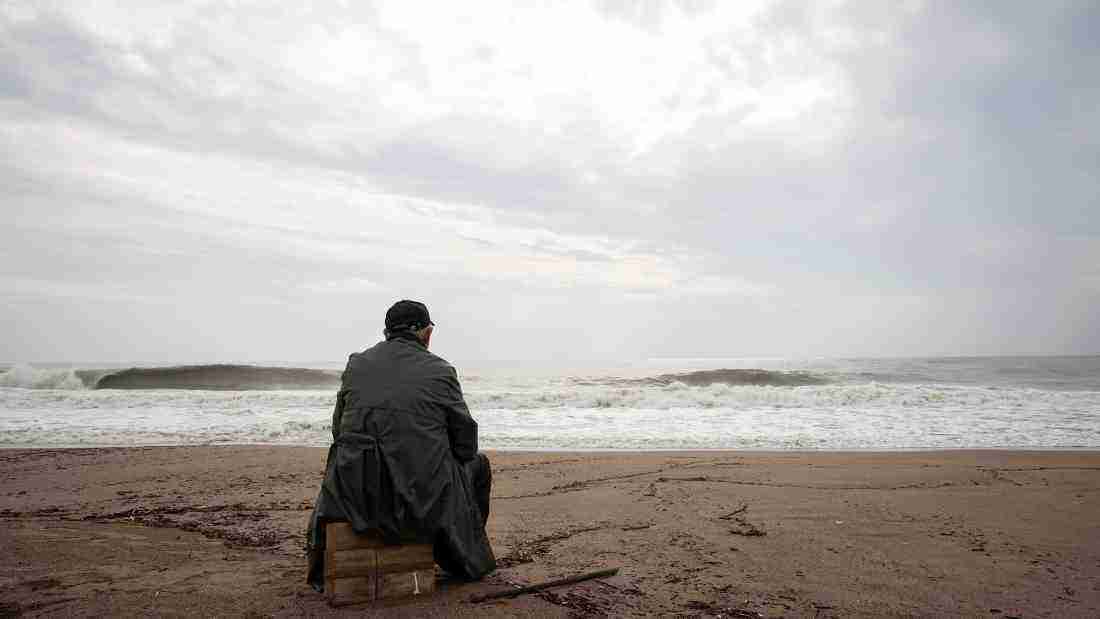 An isolated man sitting alone at the beach