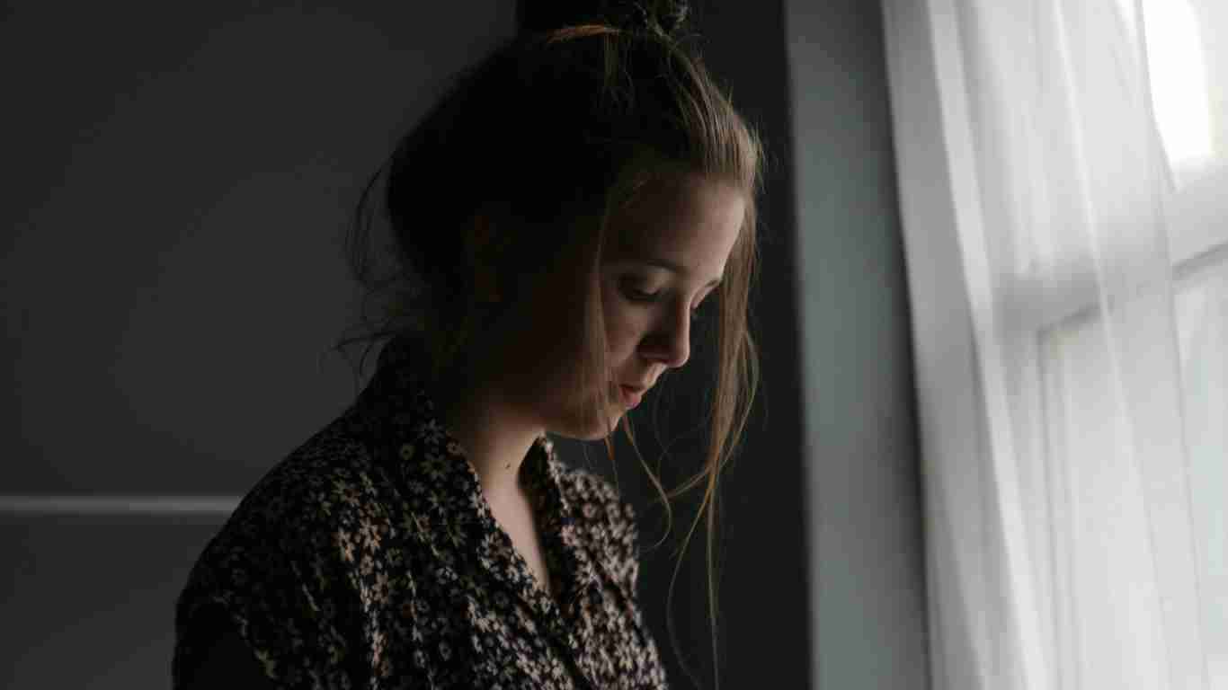 A very sad young woman looking out of a window