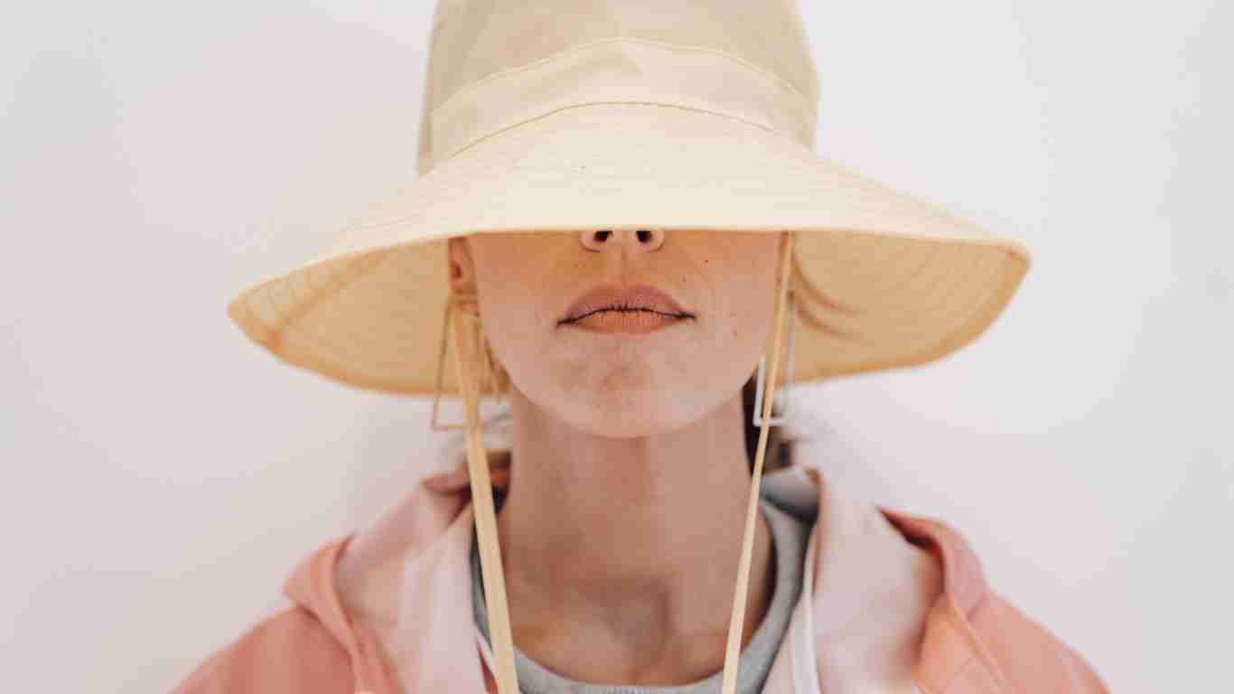 A woman covering her face with her hat