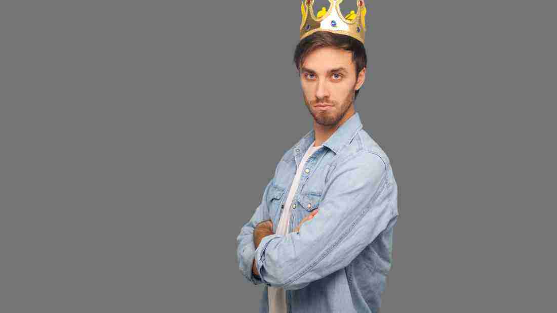 A man wearing a crown and glaring at the camera