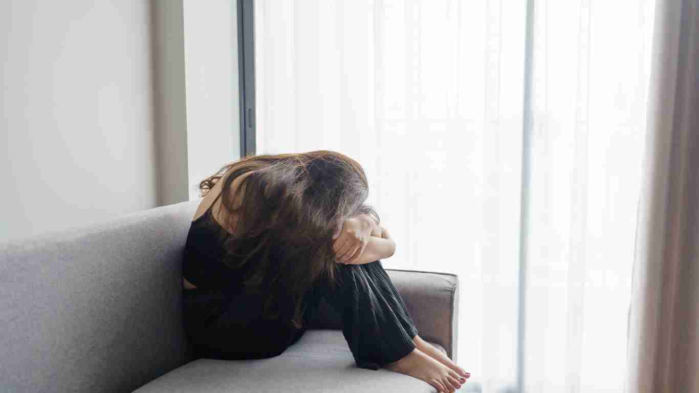 A young woman crying on a sofa
