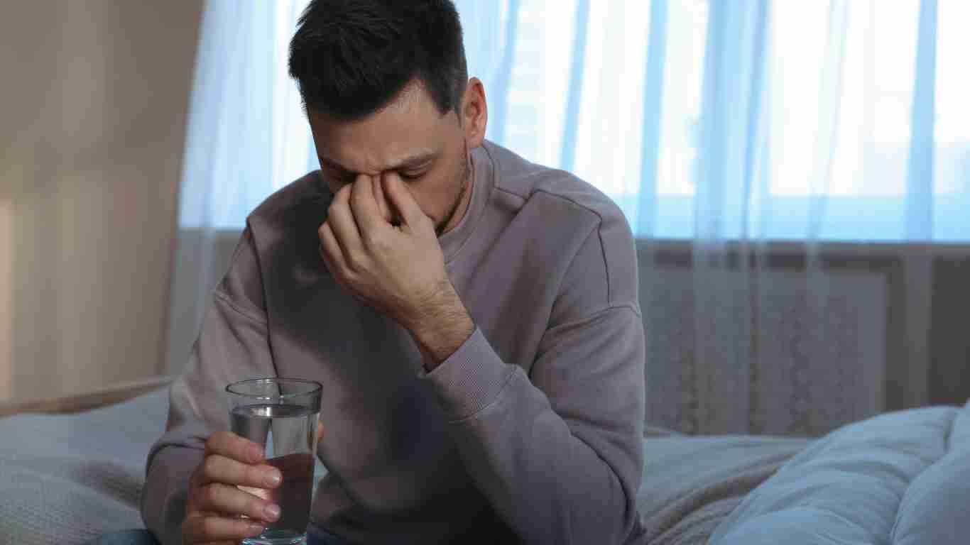 A depressed man sitting on a bed