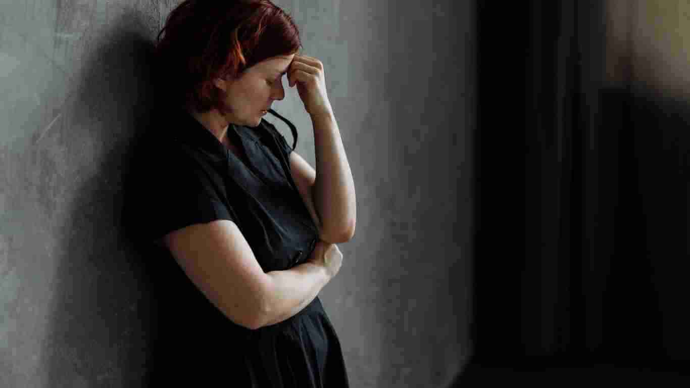 A depressed woman leaning against a wall