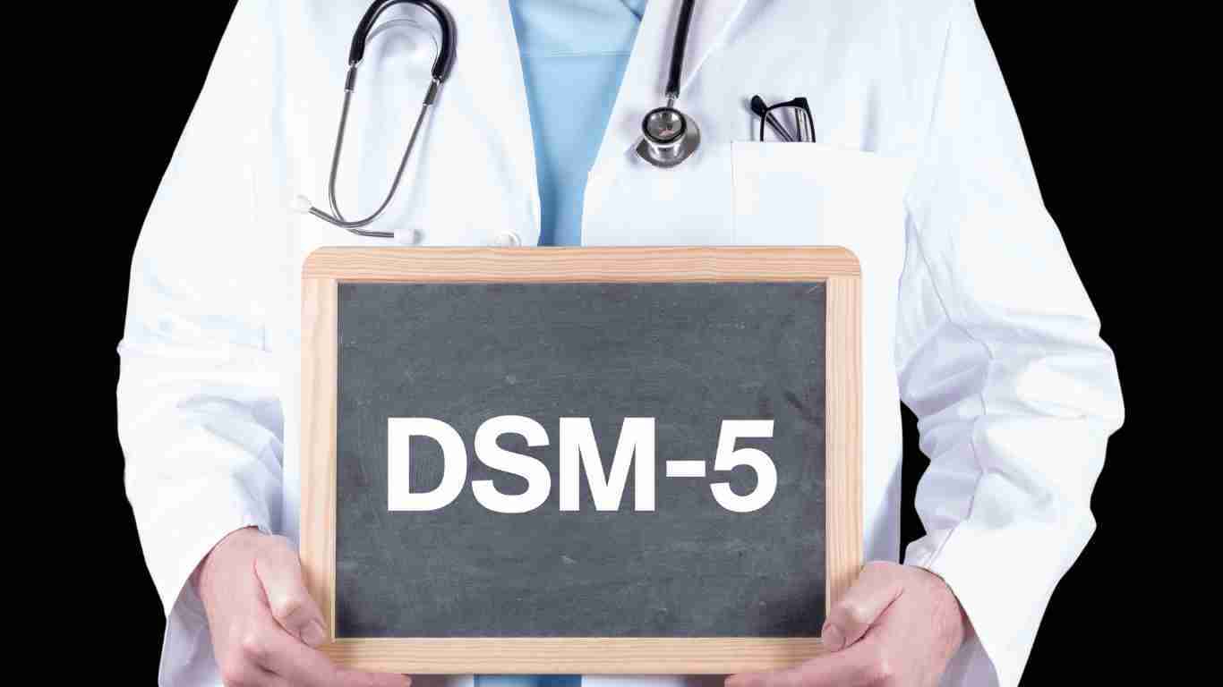 A doctor holding up a board with DSM-5 written on it