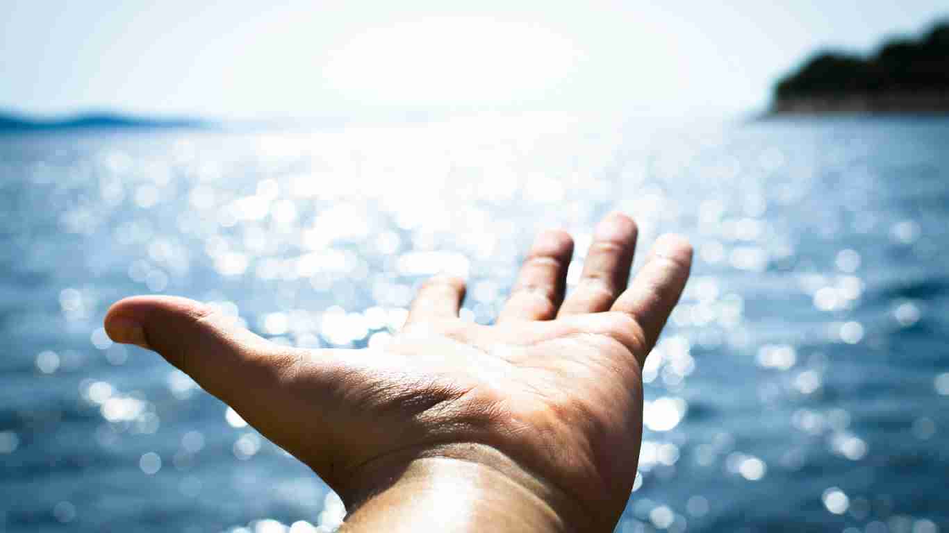A hand outstretched towards the sea, indicating hope for a better future