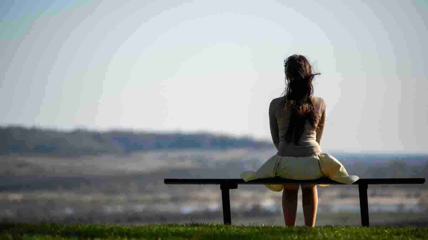 A lonely woman sitting on a bench looking very isolated