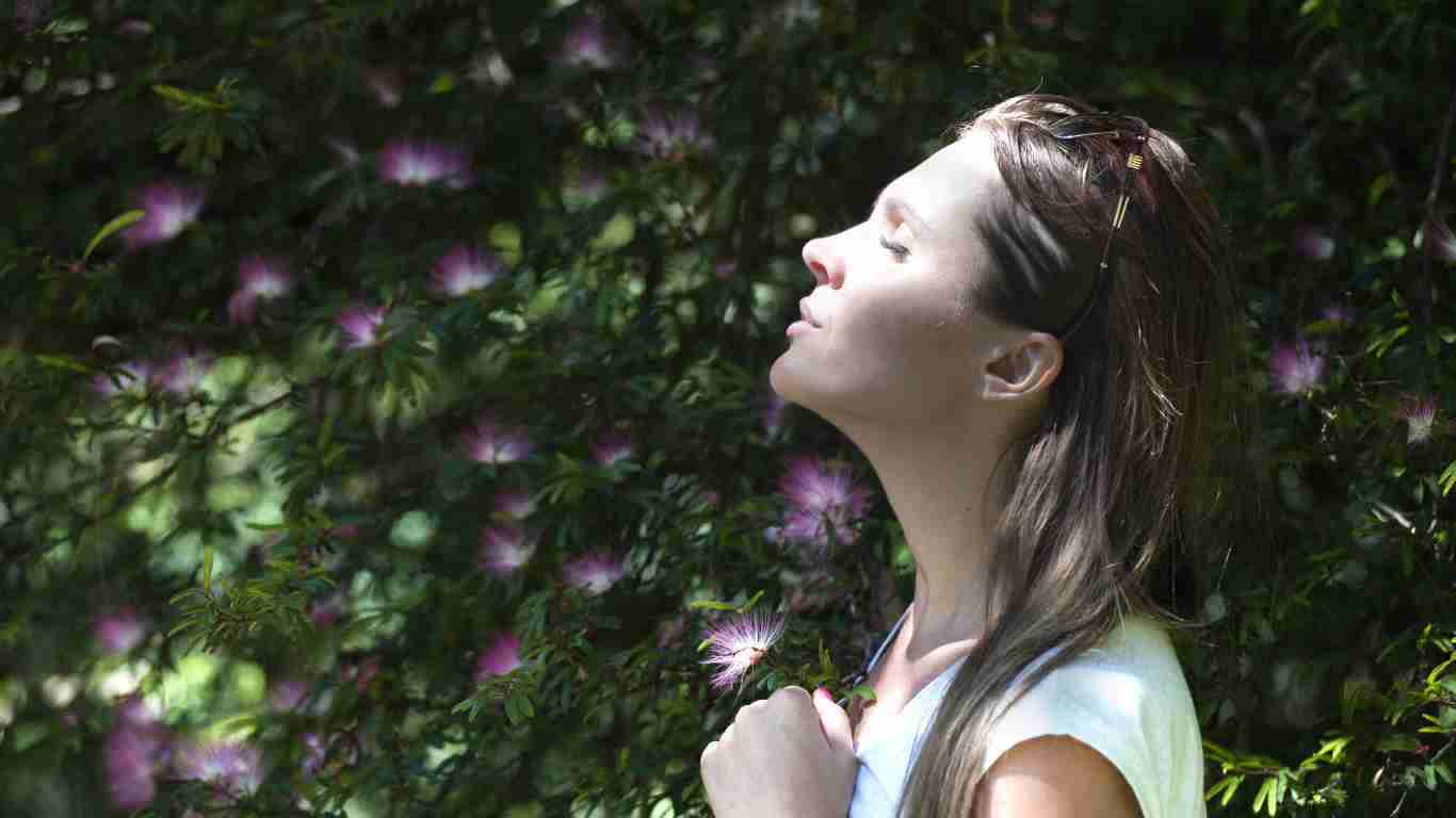 A woman enjoying the sunshine on her face in a garden